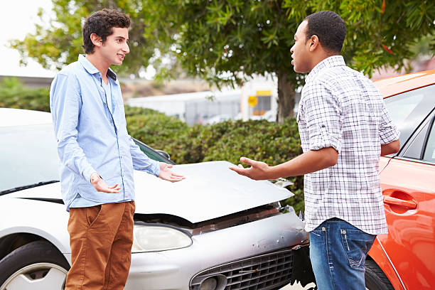two drivers arguing after traffic accident with crash in baackground.